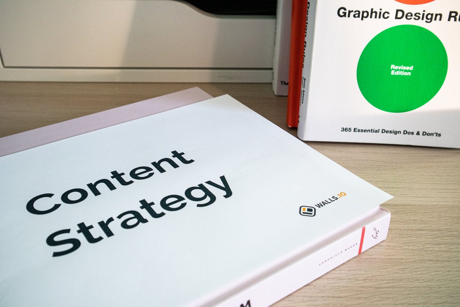 pile of books on a desk and a paper with the words content strategy on it